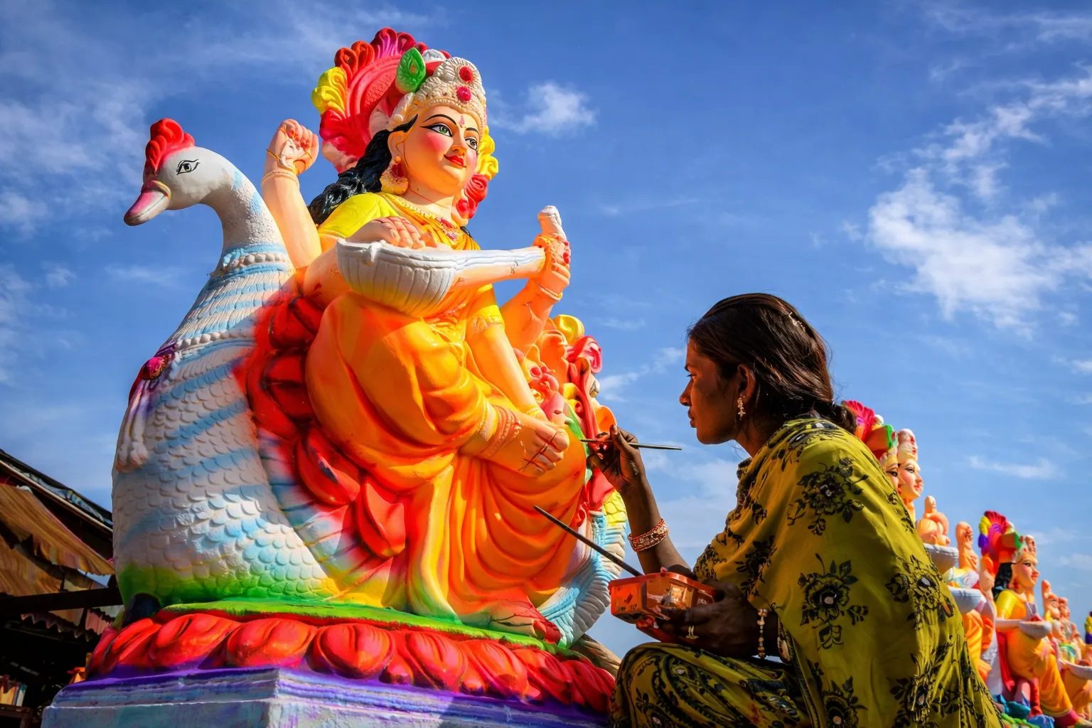 Woman painting Saraswati statue in sunlight